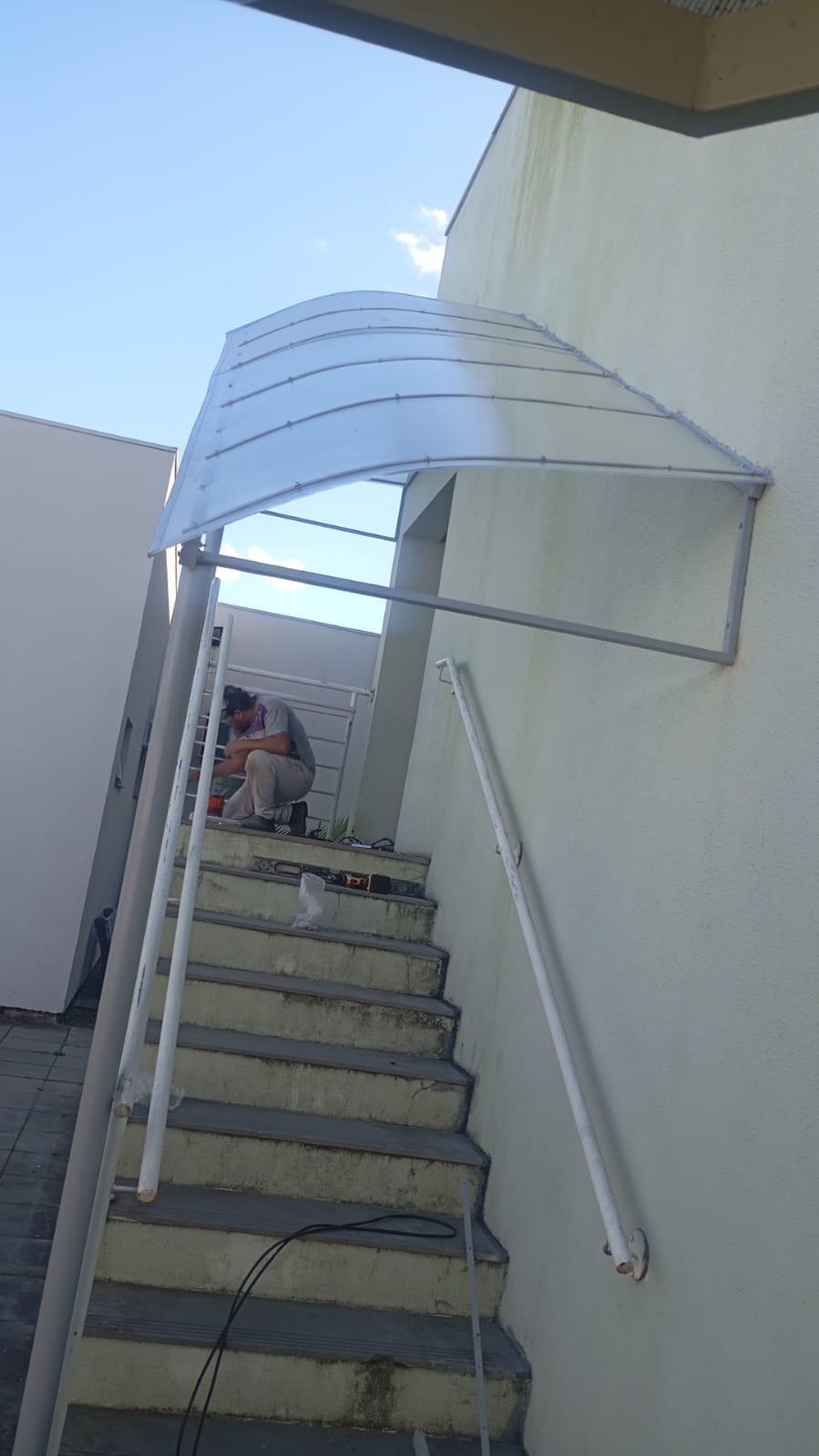 Cobertura metálica curva instalada sobre escada externa