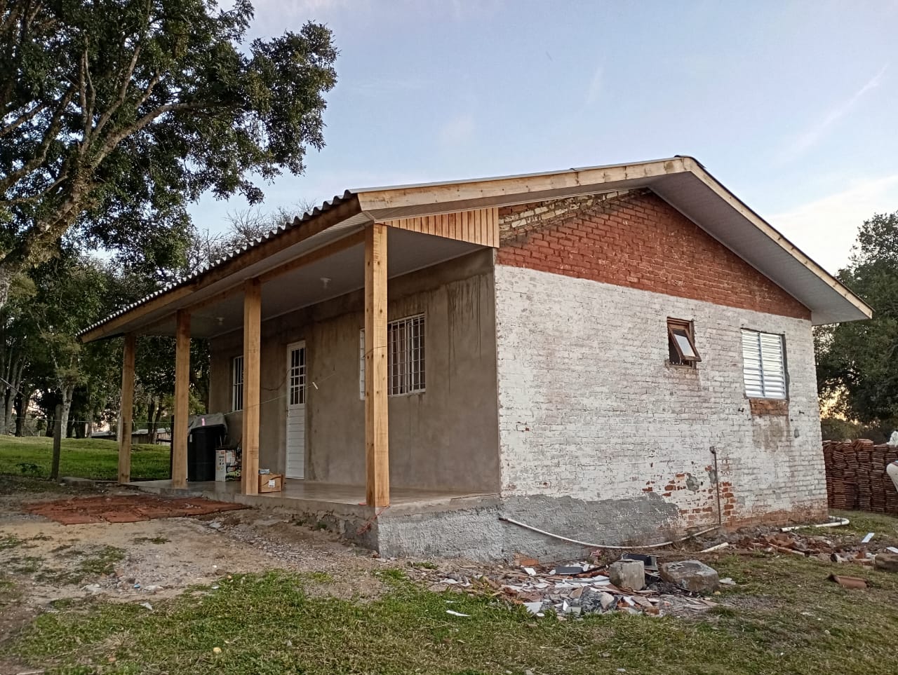 Residência em reforma com nova varanda apoiada em pilares de madeira